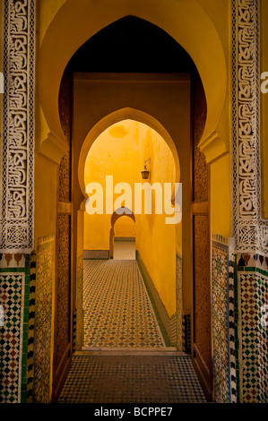 Des arcades et les murs jaune vif dans le tombeau de Moulay Ismail, Meknès, Maroc Banque D'Images