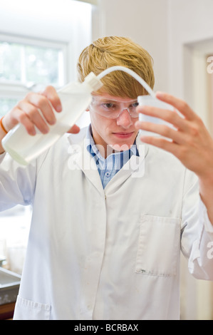 UK School England Grammar School Education - UN jeune étudiant de sexe masculin mesurant le liquide dans une leçon de science scolaire. Banque D'Images