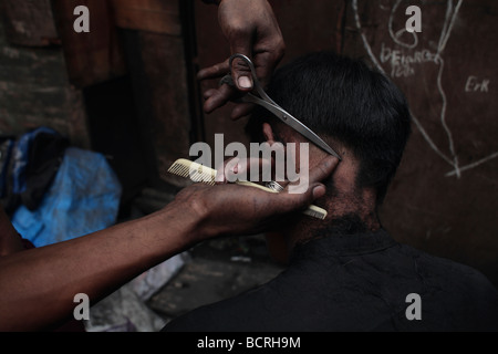 Un garçon obtient sa coupe dans les bidonvilles de Tamabakan, Tondo, Philippines Banque D'Images