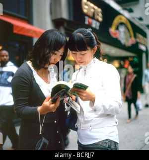 Jeunes touristes asiatiques regardant un guide de NYC et une carte sur la 5ème Avenue à New York NY USA États-Unis d'Amérique KATHY DEWITT Banque D'Images