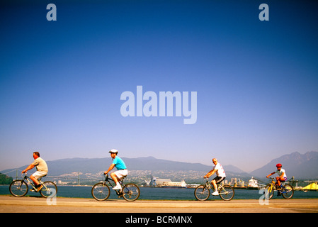 Quatre cyclistes vélo sur le Stanley Park Seawall le long de l'Inlet Burrard Vancouver British Columbia Canada Banque D'Images