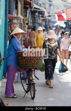 Vente de rambutan hawker femelle son vélo dans un étroit dans backstreet Cho Lon le Chinatown de Ho Chi Minh City Vietnam Banque D'Images