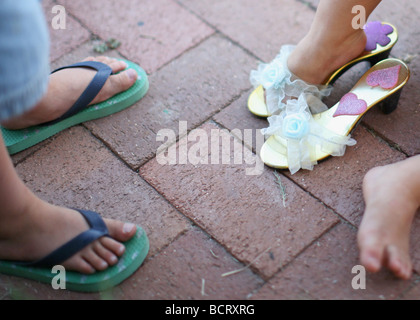 La section basse de deux enfants portant des chaussons et sandales Banque D'Images