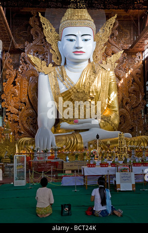 Les birmanes adorant l'énorme bouddha assis. Ngahtatgyi Paya. Yangon. Myanmar Banque D'Images