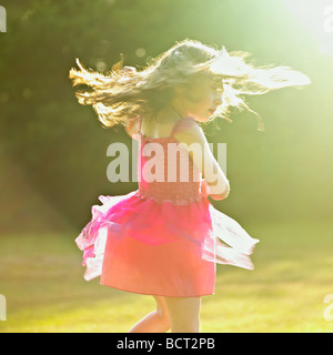 Jeune fille dans une robe rose danser dans le jardin soleil d'été. Banque D'Images