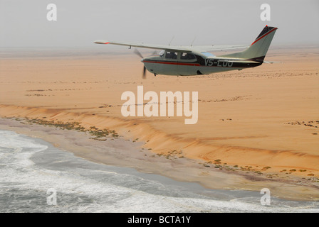 Petit avion survolant la Côte des Squelettes, Kaokoveld, Namibie, Afrique Banque D'Images