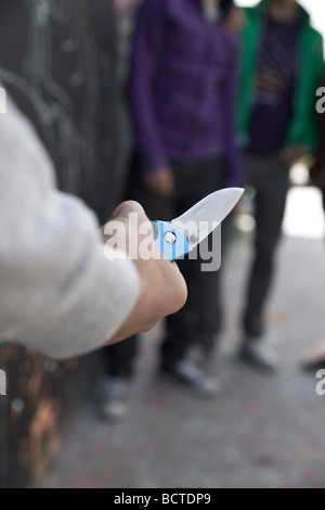 Adolescent menaçant un groupe avec un couteau Banque D'Images