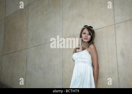 Portrait d'une jeune femme blonde en robe blanche et lunettes devant un mur de marbre Banque D'Images