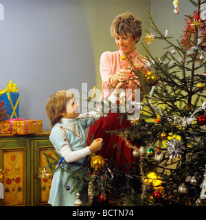 Monsieur FEMME ET LITTLE GIRL DECORATING CHRISTMAS TREE Banque D'Images