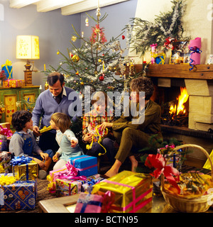 Monsieur COUPLE DONNANT DES CADEAUX DE NOËL AUX ENFANTS SOUS L'ARBRE Banque D'Images