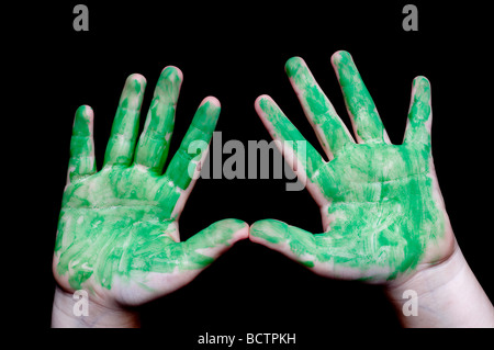 Une image horizontale d'un coverend childs mains dans de la peinture verte sur fond noir Banque D'Images