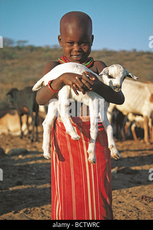Samburu jeune fille avec un grand sourire tenant une chèvre bébé près de la réserve nationale de Samburu, Kenya Afrique de l'Est Banque D'Images