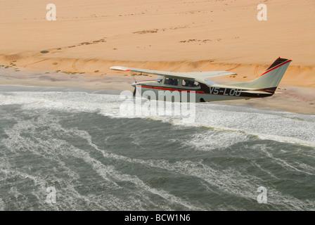 Petit avion survolant la Côte des Squelettes, Kaokoveld, Namibie, Afrique Banque D'Images