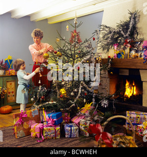 Monsieur FEMME ET LITTLE GIRL DECORATING CHRISTMAS TREE Banque D'Images