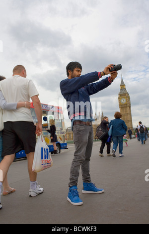 Un jeune homme asiatique prend une photographie du pont près de Big Ben Westimnster alors qu'une jolie jeune fille blonde achète une glace Banque D'Images