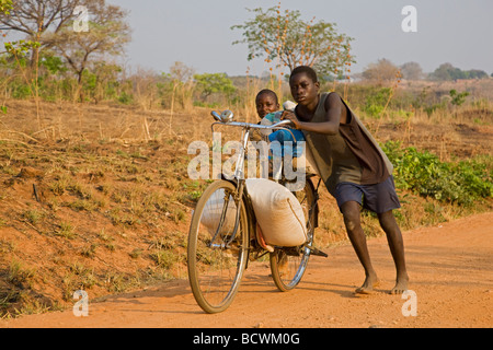 Les deux garçons de porter de lourds sacs sur une bicyclette, la Zambie, l'Afrique Banque D'Images