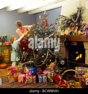 Monsieur FEMME ET LITTLE GIRL DECORATING CHRISTMAS TREE Banque D'Images