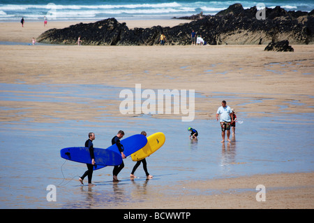 Surfers carrying surfboards sur la plage de fistral, Cornwall, uk Banque D'Images