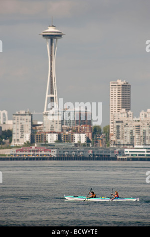 Seattle, Washington. Deux kayakistes, dans la baie Elliott, paddle passé le monument Space Needle sur une chaude soirée d'été. Banque D'Images