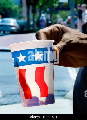 Main de personne sans-abri, la tasse de papier avec nous d'un drapeau à la mendicité pour changer sur Pennsylvania Avenue, Washington DC. Banque D'Images