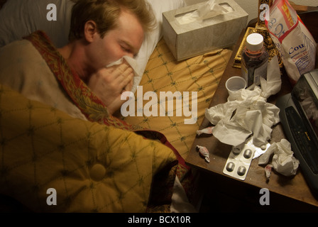 L'homme malade au lit soufflant son nez Banque D'Images