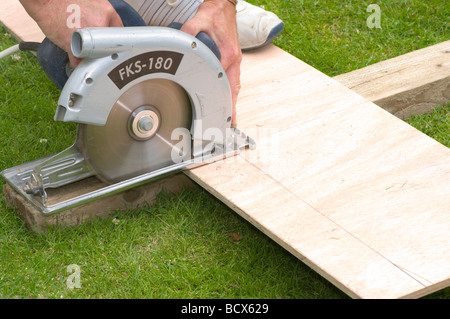 Handyman Cutting a feuille de bois en utilisant une scie circulaire Banque D'Images