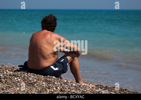 Middle aged man sitting on beach at Avdimou beach Chypre Banque D'Images