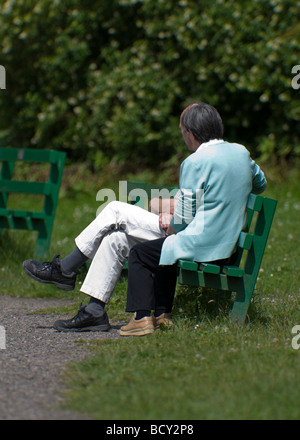 Deux personnes assises sur un banc de parc engrosed in conversation. Banque D'Images