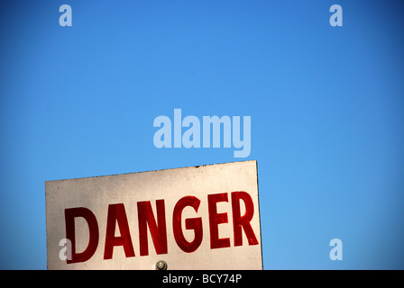 Panneau blanc avec rouge type disant danger avec ciel bleu en arrière-plan Banque D'Images