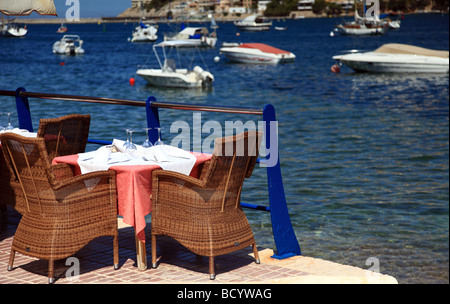 Un restaurant table à côté de la mer sur un mur du port Banque D'Images