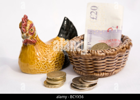 Des crédits sont mis à côté d'une poule en céramique. Une poule similaire a été utilisée pour la famille pour placer de l'argent dans la télévision britannique,pain série Banque D'Images