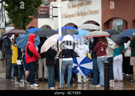 Les visiteurs à Stratford upon Avon braver les intempéries de l'été britannique sous leur umberellas. Banque D'Images