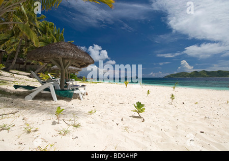 Chaise longue et parasol, l'eau claire, de sable, à l'établissement Matamanoa Island Resort Fidji Îles Mamanuca Banque D'Images
