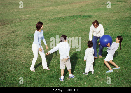 Family Playing with ball in grassy field Banque D'Images