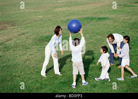 Family Playing with ball in grassy field Banque D'Images