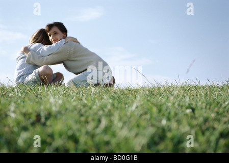 Fille embrassant son jeune frère in grassy field