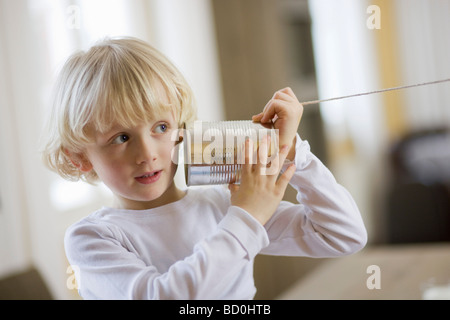 Jeune garçon jouant avec can téléphone Banque D'Images