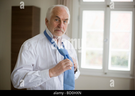 Old man putting on tie Banque D'Images