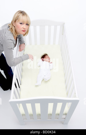 Souligné mère regardant bébé dans Lit bébé Banque D'Images