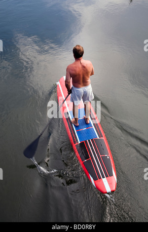 Aman sur un paddleboard standup, flotteurs les eaux fraîches de la rivière Deschutes dans le Old Mill District dans la région de Bend Oregon Banque D'Images