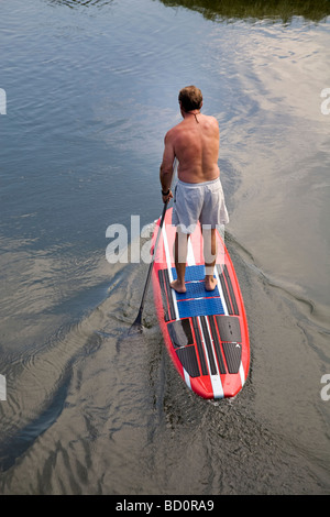 Aman sur un paddleboard standup, flotteurs les eaux fraîches de la rivière Deschutes dans le Old Mill District dans la région de Bend Oregon Banque D'Images