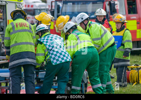 Les équipes de pompiers et les ambulances se déplacer sur une personne blessée à un chariot après un grave accident de la route Banque D'Images