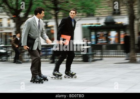 Les hommes et femmes d'roller ensemble le long trottoir carrying briefcase, dossiers sous le bras Banque D'Images