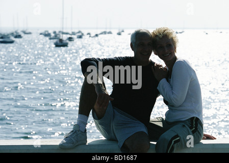 D'âge mûr assis ensemble sur pier, rétroéclairé Banque D'Images