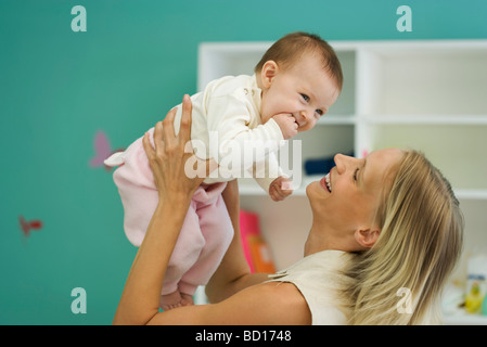 Jeune mère holding up baby, smiling Banque D'Images