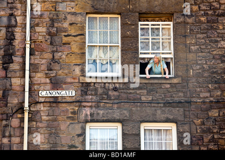 Une vieille femme regarde par sa fenêtre sur Canongate, Édimbourg, Écosse Banque D'Images