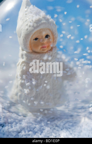 Snow globe, figurine de little girl wearing hat manteau d'hiver et à la chute de flocons de neige Banque D'Images