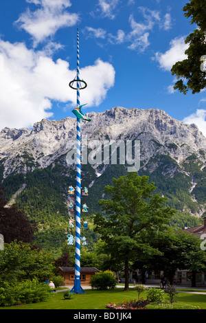 Un Maypole allemand traditionnel avec des symboles commerciaux avec des montagnes derrière dans la ville de Mittenwald, Bavière, Allemagne, Europe Banque D'Images