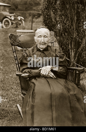 L'ancienne femme assise dans un fauteuil à bascule à l'extérieur Banque D'Images