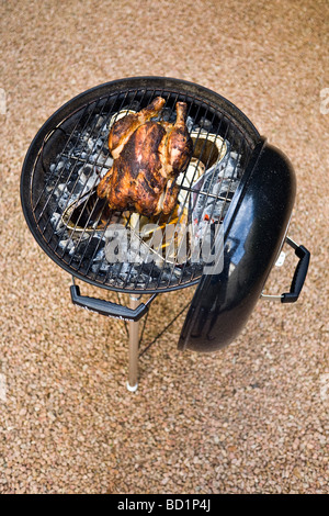 Le grillage d'un poulet fermier grâce à un barbecue. Cuisson d'un poulet fermier dans un barbecue à couvercle. Banque D'Images